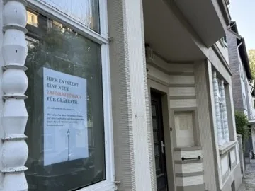 Plakat im Schaufenster: Hier entsteht eine neue Zahnarztpraxis für Gräfrath