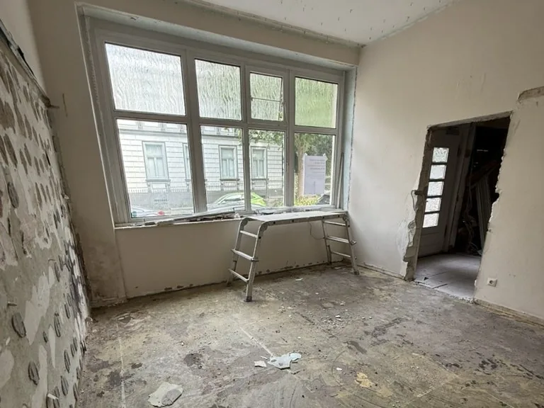 Baustelle im Erdgeschoss: entkernter Raum mit großem Fenster